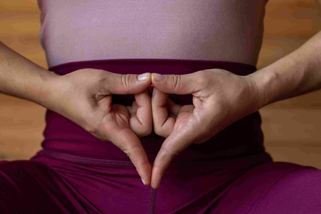 Hands forming a yoni mudra gesture over a woman’s lower abdomen, symbolizing sacred feminine energy and yoni healing in Sri Lanka.