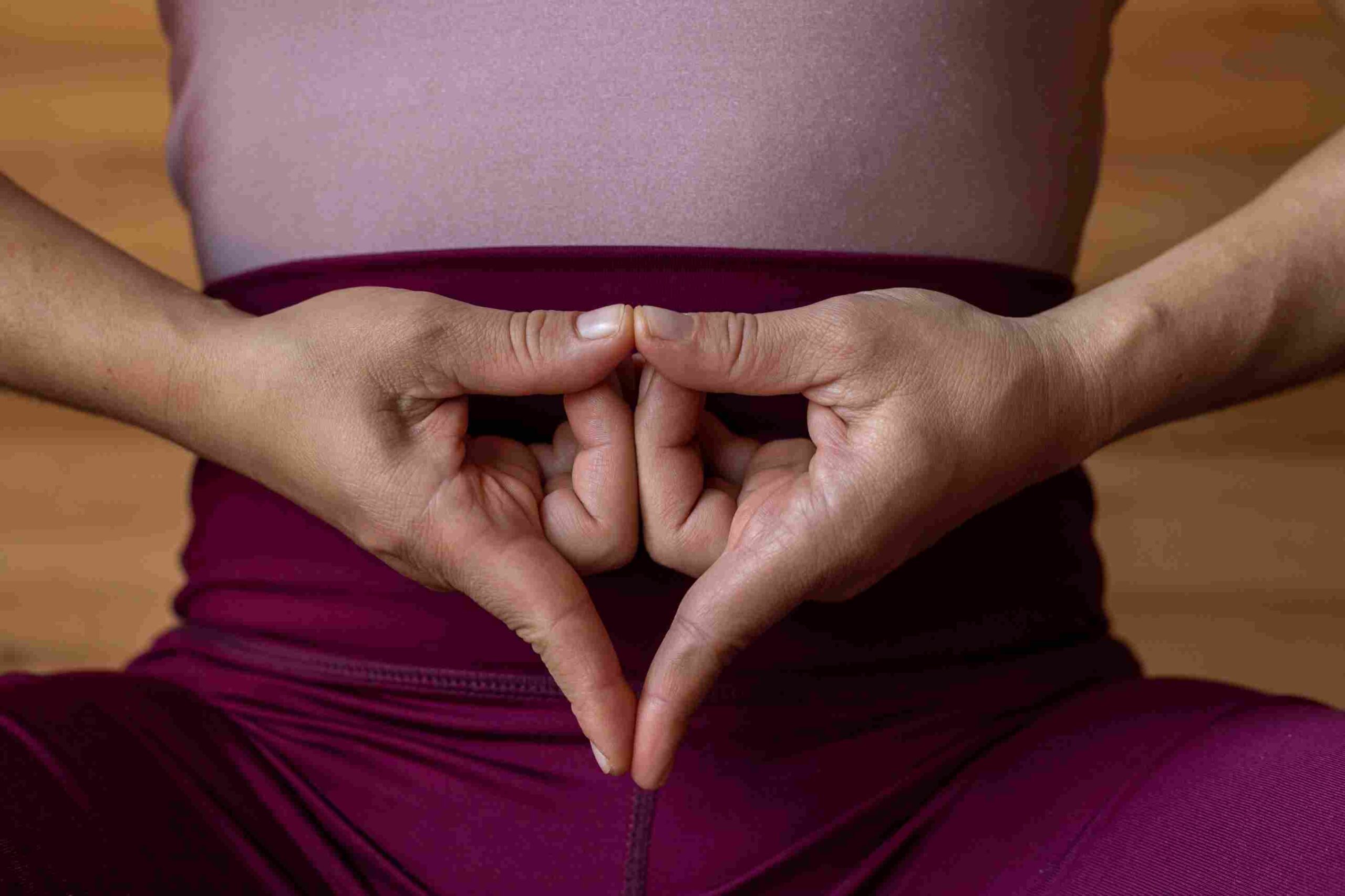 Hands forming a yoni mudra gesture over a woman’s lower abdomen, symbolizing sacred feminine energy and yoni healing in Sri Lanka.